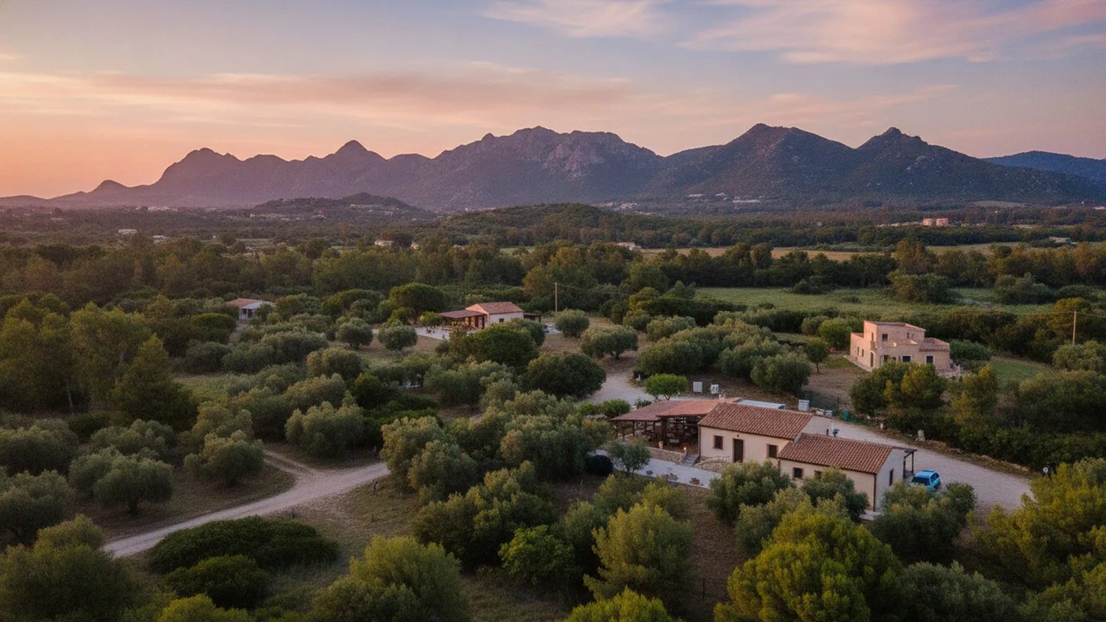 La campagna verso Cala Sinzias, tra case sparse e macchia mediterranea, con le montagne sullo sfondo